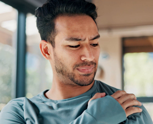 Male holding his left shoulder with a look of pain on his face