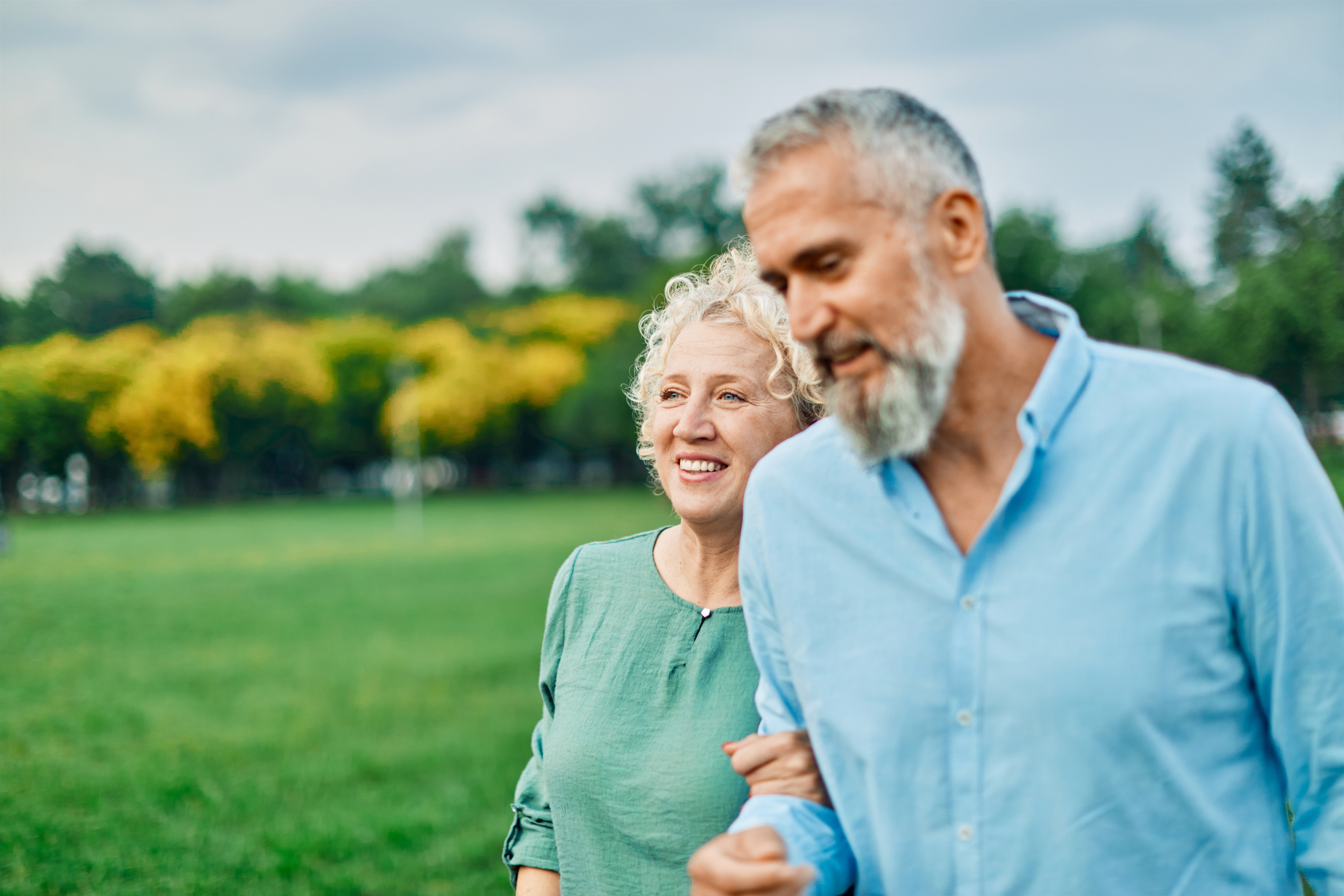 Two older adults walking together in a green park, promoting healthy ageing, active lifestyle, outdoor exercise, wellbeing, and senior health.